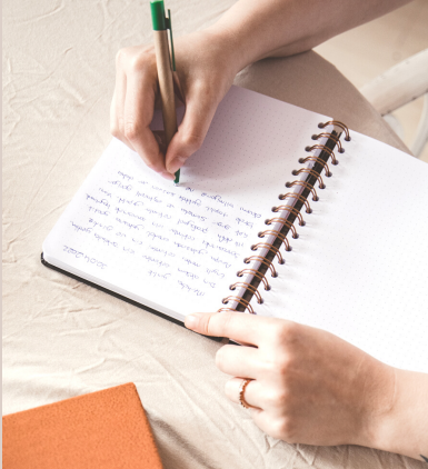Photo d'une femme qui écrit dans son cahier lors de son rendez-vous d'auto-coaching hebdomadaire