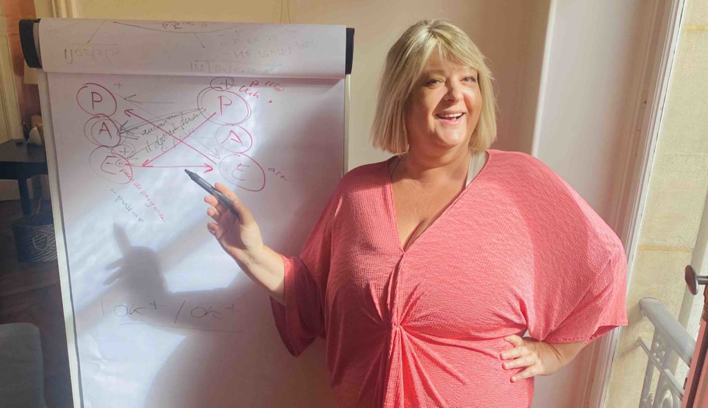 Chine Lanzmann est coach professionnelle, elle fait du coaching et des formation au leadership pour les femmes, elle est devant un paperboard en coaching collectif